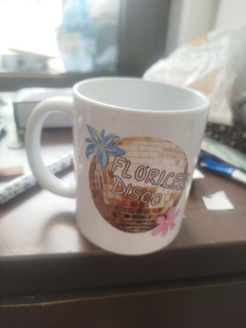 Custom white mug with Florice Disco logo featuring a gold disco ball and flowers